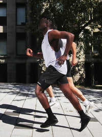 A full body picture of two people running in an urban area. One can clearly be seen wearing the legband sold by 800m.