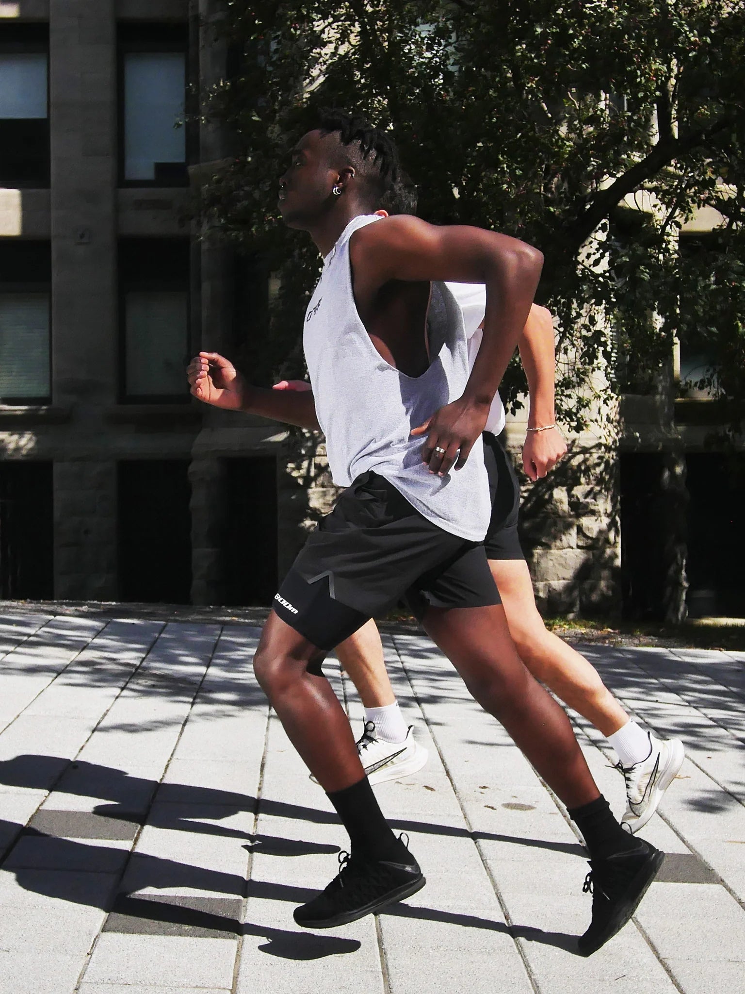 Two runners in an urban setting; one is wearing the 800m thigh phone holder under running shorts