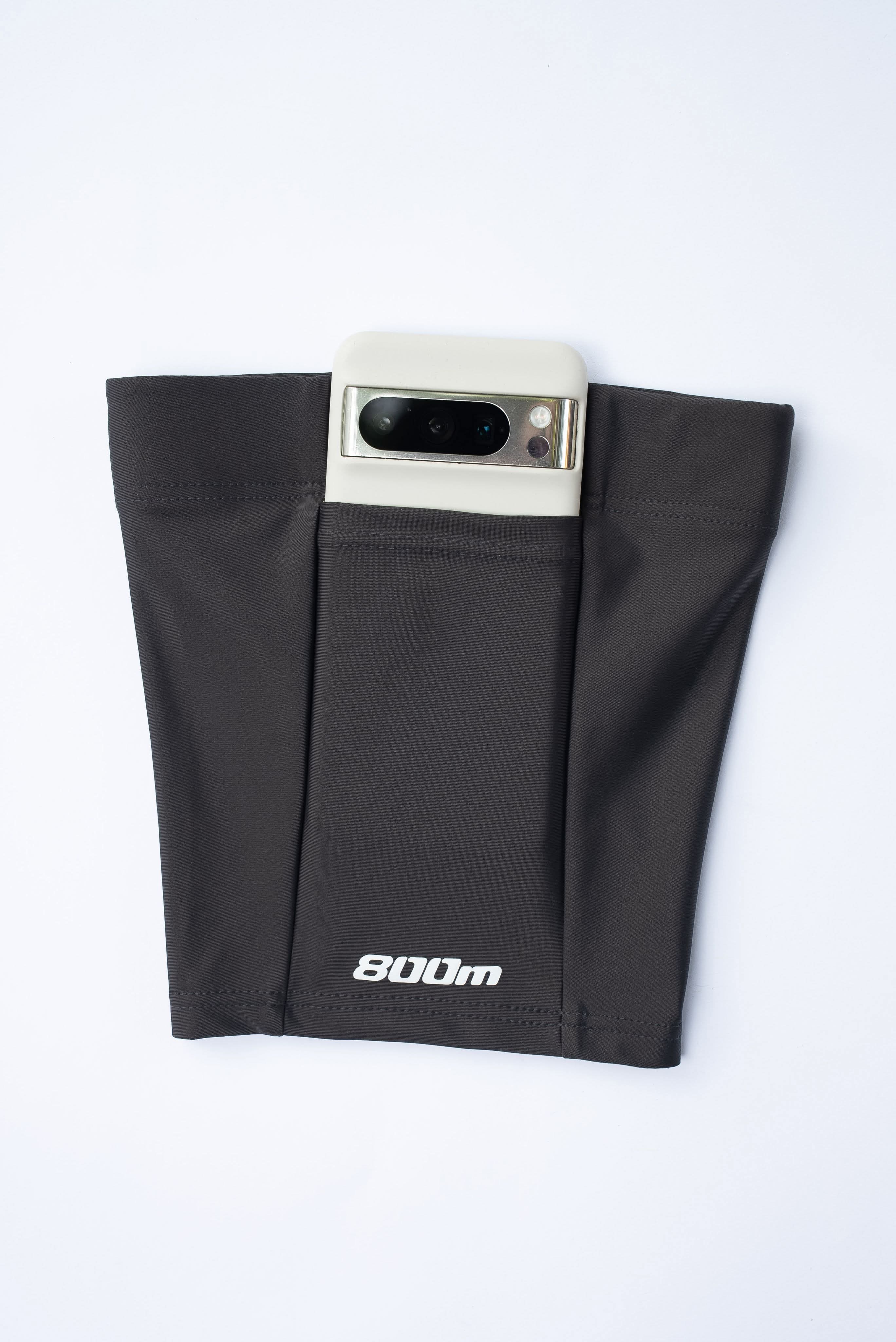 Phone being inserted into the pocket of the black 800m THIGHBAND running phone holder.